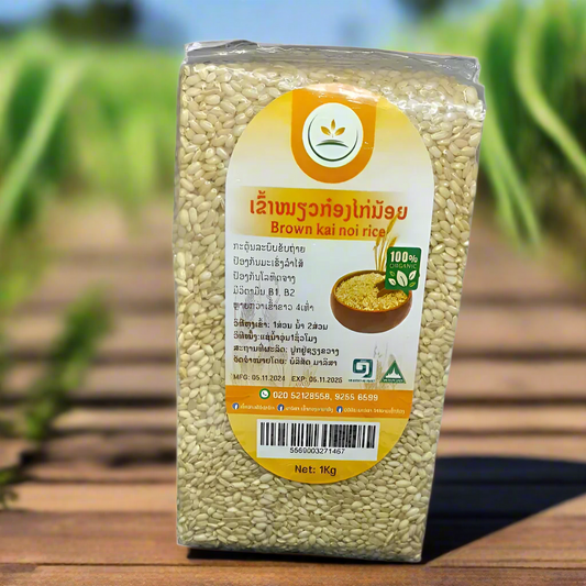 A vacuum-sealed package of Brown Kai Noi Rice, 1 kg size, with a label displaying product information and the brand logo, set against a natural background.