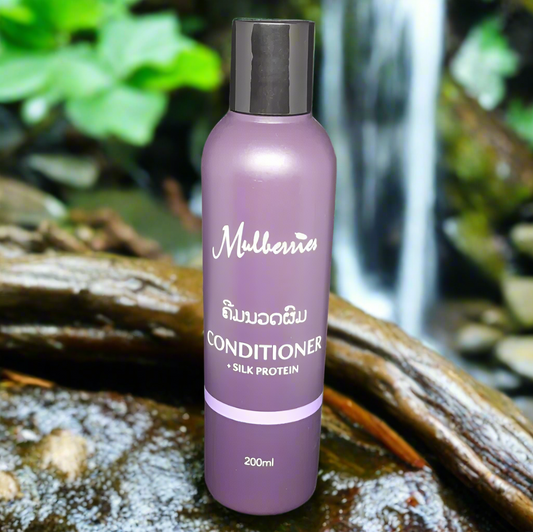 A bottle of Mulberries Silk Protein Conditioner in a 200ml size, with a purple label and cap, placed on a natural background with a waterfall and greenery.