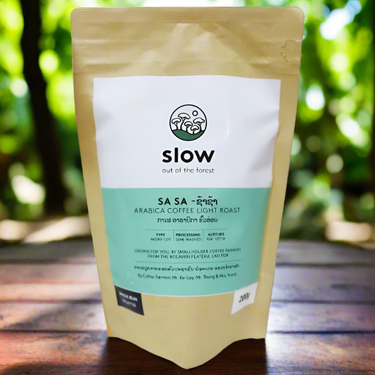 A bag of SLOW Sa Sa Arabica Coffee Light Roast displayed in front of a natural background with trees.