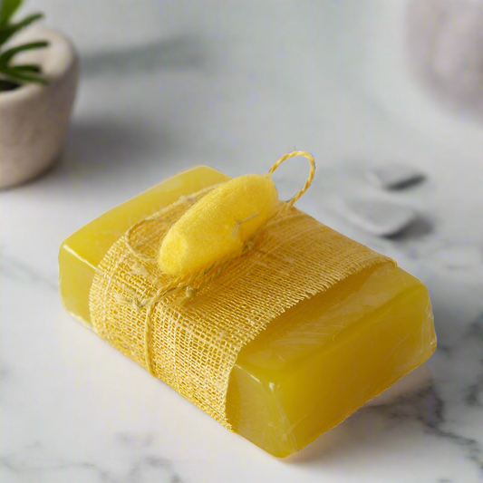 A bar of yellow soap wrapped in brown paper with a yellow string, placed on a white marble surface.