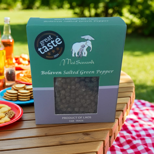 Box of Bolaven Salted Green Pepper on a picnic table with snacks and drinks.