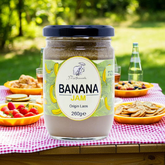 Jar of banana jam on a picnic table with snacks and drinks
