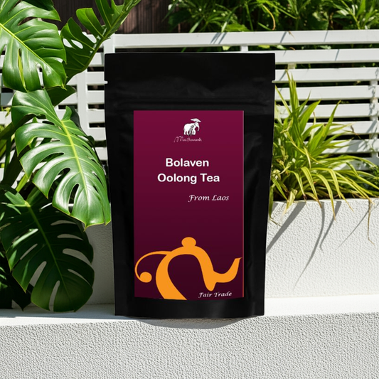 Tea bag labeled 'Bolaven Oolong Tea From Laos' with a brand logo, set against a natural background with plants.